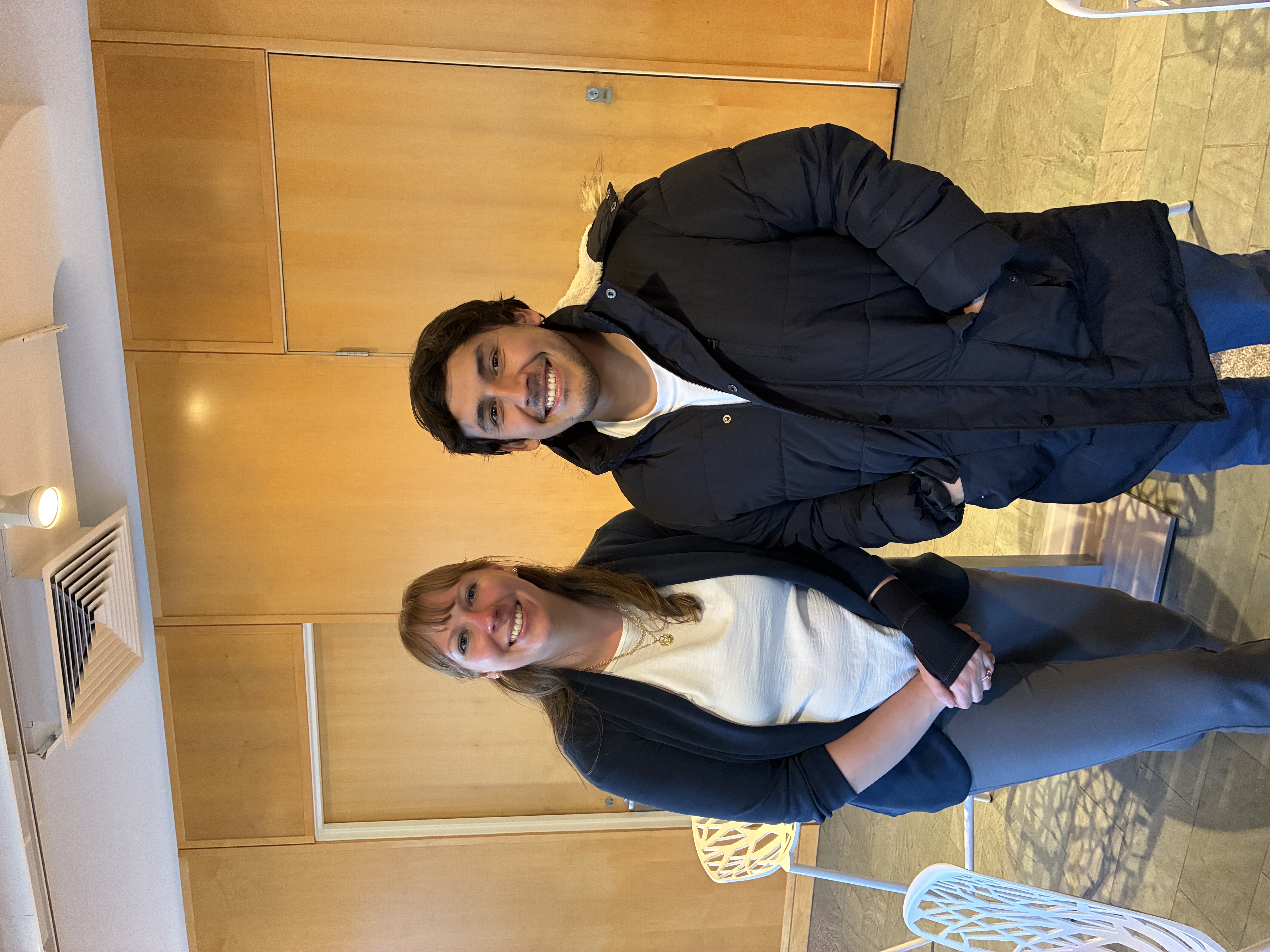 Isabel Deibel and Martín Sosa standing together in a wood-paneled room